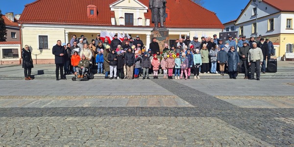 dzieci pozują do zdjęcia pod pomnikiem.jpeg