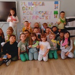 zdjęcie grupowe na tle tablicy z kolorowym napisem 