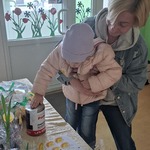 Mama z dziekiem na rękach wrzuca datek do puszki 