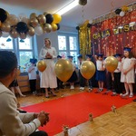 pani dyrektor stoi na scenie obok balonów i dzieci.jpeg