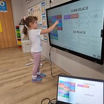 Dziewczynka wykonuje zadanie na tablicy multimedialnej
