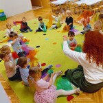 dzieci siedzą na dywanie i machaja kolorowymi chustkami.jpg