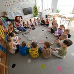dzieci siedzą na dywanie i patrzą co pokazuje im pani.jpg