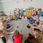 dzieci siedzą na dywanie i trzymają w rękach drewniane instrumenty.jpg