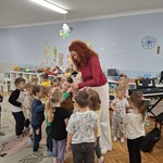 dzieci stoją na podłodza a pani przybija im pieczątki na rękach.jpg