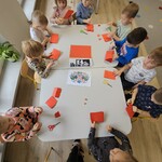 dzieci wycinają kolorowe kartki przy stoliku.jpg