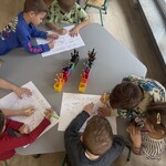 dziewczynki i chłopcy kolorują mapę przy stoliku.jpg
