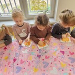 dziewczynki siedzą przy stoliku i wyklejają obrazek dyni.jpg