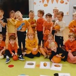 dzieci w pomarańczowych ubraniach stoją na dywanie.jpg