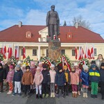 dzieci razem z nauczycielką stoją pod pomnikiem.jpg