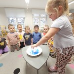 dziewczynka trzyma szklankę nad talerzem i robi eksperyment.jpg