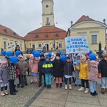 dzieci i panie stoją przed ratuszem z niebieskimi balonami.jpg