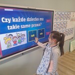 dziewczynkami stoi przed tablicą multimedialną.jpg