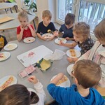 Dzieci przygotowują mini pizze przy stoliku 