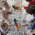 Dzieci wykonują pracę plastyczną przy stolikach 