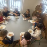 Dzieci degustują zrobioną pizzę siedząc przy stoliku 