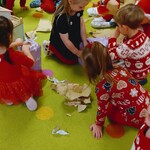 dzieci na dywanie rozpakowują świąteczne prezenty.jpg