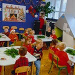 dzieci siedzą przy stolikach przed nimi leżą rzeczy do robienia wianków.jpg