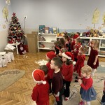 dzieci stoją na dywanie przed nimi choinka i prezenty.jpg