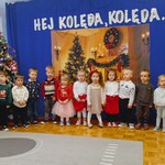 dzieci stoją na scenie przy choince i napisie o kolędzie.jpg