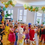 Wszystkie dzieci tańczą na sali udekorowanej zielonymi balonami 