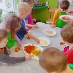 dzieci układają składniki na swoje mini pizze.jpg