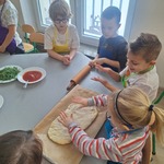 dziewczynka układa placek na pizzę na papierze do pieczenia.jpg