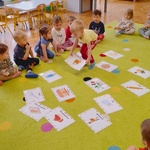 dzieci siedzą na dywanie na którym leżą obrazki związane z pizzą.jpg