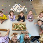 dzieci siedzą przy stoliku przed nimi leży pizza.jpg