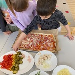 chłopoiec układa warzywa na pizzy.jpg