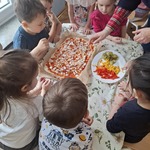 dzieci razem z nauczycielką układają składniki na pizzy.jpg