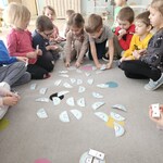 dzieci siedzą na dywanie i układają kolorowe obrazki.jpg