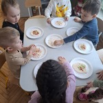 dzieci siedzą przy stoliku i mają przed sobą talerzyki z kolorową masą.jpg