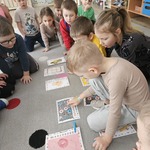 chłopiec pokazuje palcem na obrazek który leży przed nim.jpg
