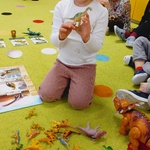 dziewczynka w białej bluzce trzyma zabawkę dinozaura.jpg
