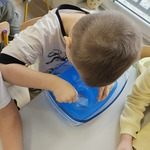 chłopiec wkłada szklankę do niebieskiej wody.jpg