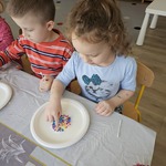 Dziewczynka robi kolorowe plamki na mleko nalanym do talerza