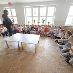 dzieci siedzą na podłodze i patrzą na panią.jpg