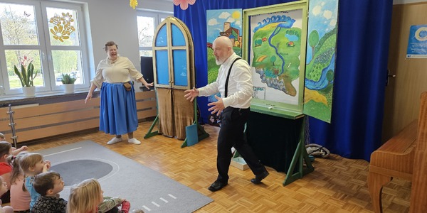aktorzy stoją na scenie na tle kolorowych dekoracji.jpg