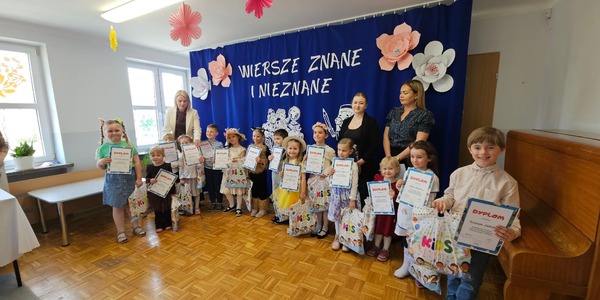 dzieci stoja na scenie w rękach trzymają dyplomy i torby.jpg