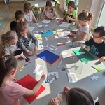 dzieci siedzą przy stole i wycinają kształty z kolorowego papieru.jpg