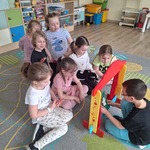 dzieci siedzą na dywanie i oglądają tearzyk z maskotką kota.jpg