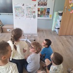 dzieci siedzą na podłodze i oglądają obrazki na tablicy.jpg