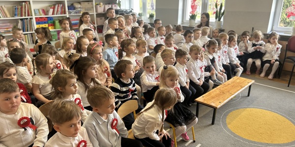 dzieci siedzą na krzesłach w odświętnych strojach.jpeg
