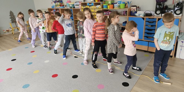 dzieci stoją w rzędzie na dywanie na którym leżą skakanki.jpg