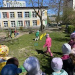 dzieci stoją na placu zabaw chłopiec biegnie między żółtymi pachołkami.jpg