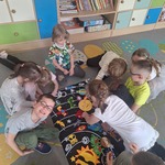 dzieci przypinają planety na macie z kosmosem.jpg