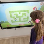 dziewczynka stoi przy tablicy multimedialnej na której jest zielony labirynt.jpg