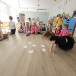 dzieci siedzą na podłodze na której leżą białe kartki.jpg
