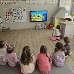 dzieci siedzą na podłodze i oglądają film edukacyjny.jpg